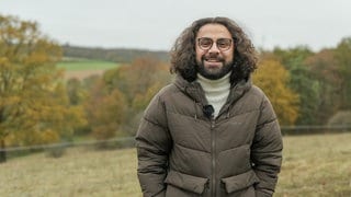 Ali auf einer seiner liebsten Spazierstrecken mit Blick auf den Fernsehturm in Stuttgart, er lächelt in die Kamera.