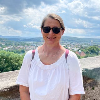 Wir treffen Caroline zufällig in Tübingen. Sie arbeitet im Pflegebereich. Sie steht am Schloss Hohentübingen und lächelt in die Kamera.