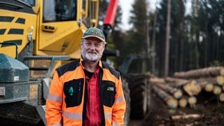 Mann Mitte 50 in einem roten Arbeitsanzug auf einer gerodeten Lichtung vor seinem Rückezug.