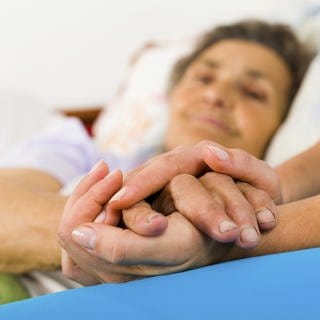 Eine Krankenschwester hält die Hand einer älteren Frau