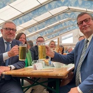 Minister Peter Hauk und OB Peter Kurz (l.) stoßen auf dem Maimarkt mit einem Bier an.