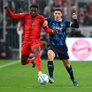 Alphonso Davies (li.) von München und Luca Kerber von Heidenheim kämpfen um den Ball