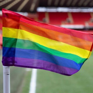 Eine Eckfahne in einem Fußballstadion in Regenbogen-Optik.