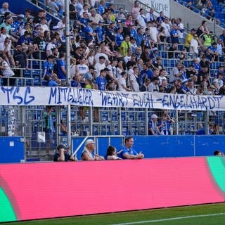 Fans der TSG 1899 Hoffenheim zeigen in der Fankurve ein Banner.