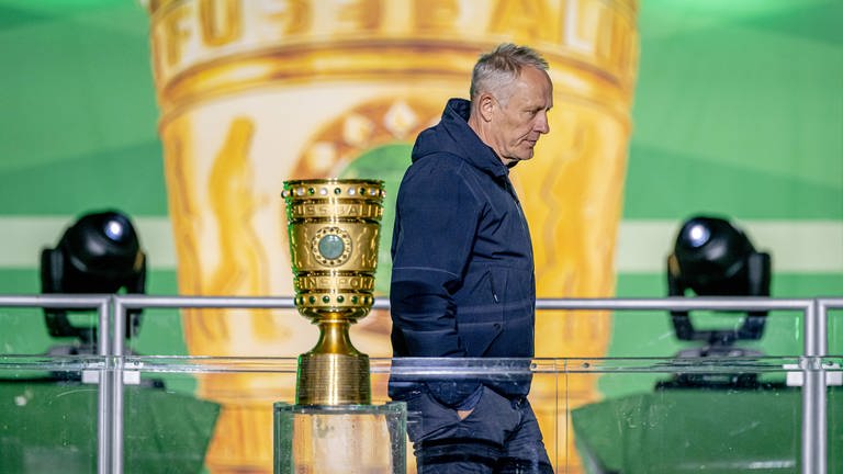 Christian Streich läuft mit hängendem Kopf am DFB-Pokal vorbei.
