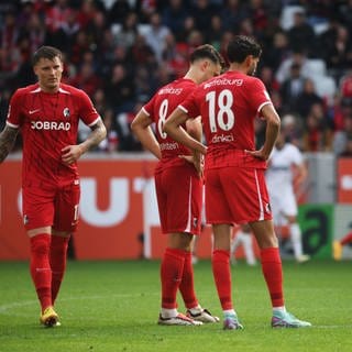 Freiburgs Lukas Kübler, Maximilian Eggestein und Eren Sami Dinkci (l-r) stehen auf dem Spielfeld.