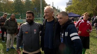 Christian Streich posiert mit zwei Straßenfußballern für ein Foto