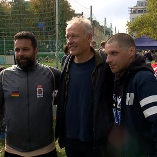 Christian Streich posiert mit zwei Straßenfußballern für ein Foto