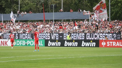 Fans des VfB Suttgart halten ein Banner hoch und zeigen damit Kritik an der Sponsorenauswahl des VfB.