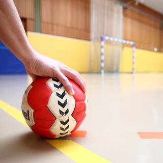 In einer Sporthalle liegt ein Handball auf dem Boden.