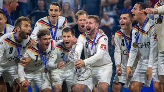 Deutschlands Faustballer jubeln mit dem WM-Pokal.
