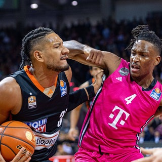 Der Ulmer Karim Jallow im schwarzen Trikot im Zweikampf gegen Phlandrous Fleming der Baskets Bonn.