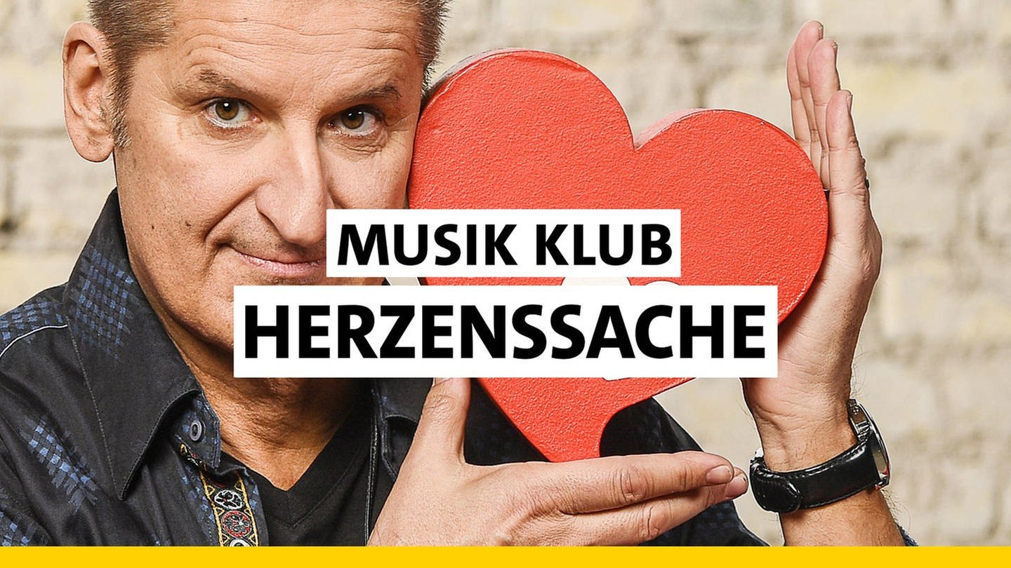 PUR-Sänger Hartmut Engler hält ein rotes Herz aus Holz in seinen Händen - das Symbol der Kinderhilfsaktion SWR Herzenssache. Darüber der Text 