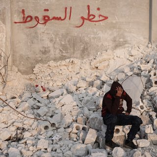 Der 15-jährige Muhammad Al-Mula sitzt in der Nähe seines zerstörten Hauses, das durch das Erdbeben an der türkisch-syrischen Grenze zerstört wurde. Al-Mula wurde gerettet, nachdem er fast zehn Stunden lang unter den Trümmern des Gebäudes eingeschlossen war, in dem er mit seinen fünf Familienmitgliedern gelebt hatte.