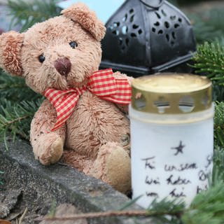 Auf einem Kindergrab im "Garten der Sternenkinder", dem Teil des Friedhofs des Alten St.-Matthäus-Kirchhofs für gestorbene Kinder, sind ein Teddybär und ein Grablicht zu sehen.