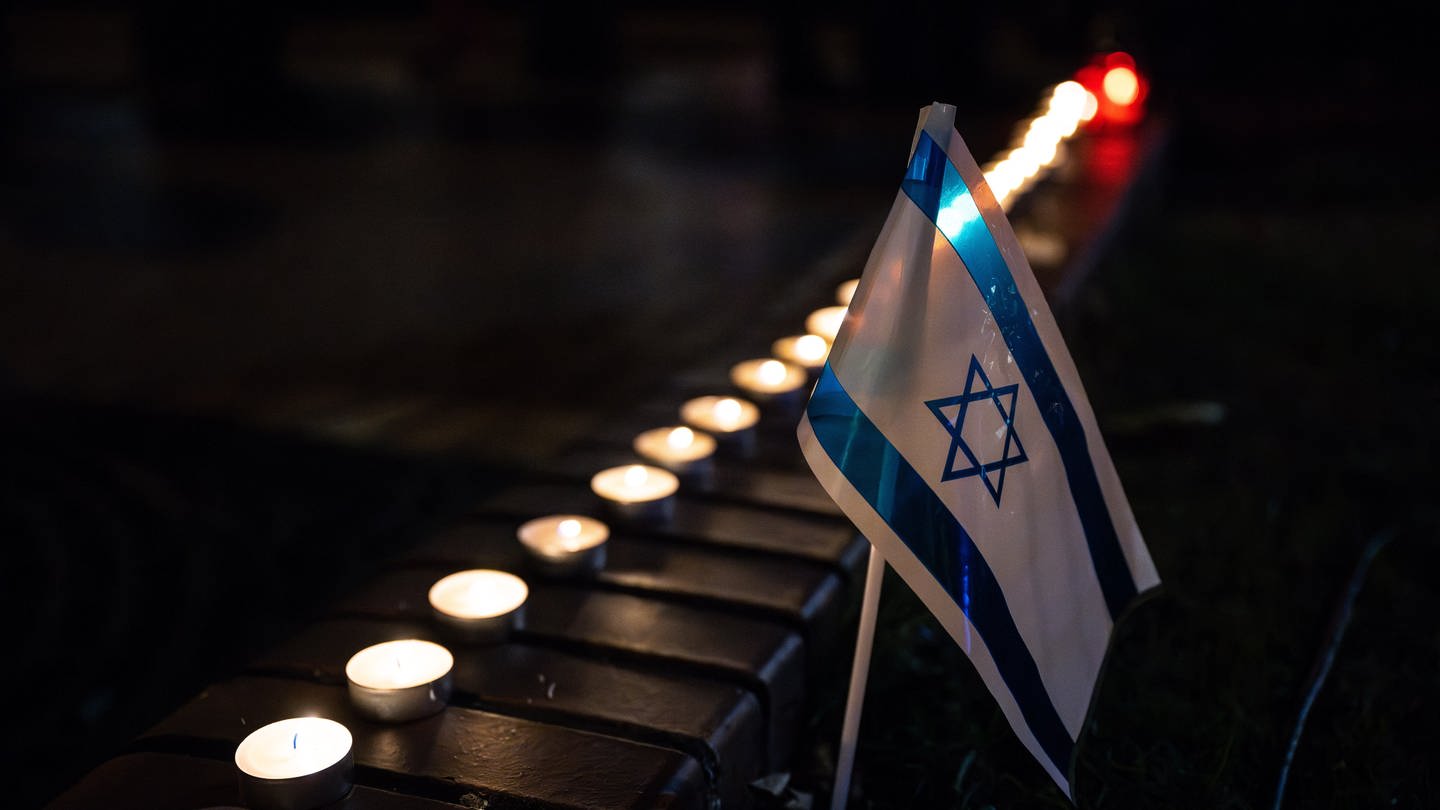 Eine israelische Fahne ist während einer Gedenkfeier neben Kerzenlichtern zu sehen.