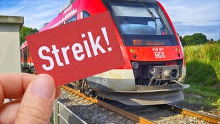 Hand hält Schild mit Aufschrift Streik vor einer Bahn