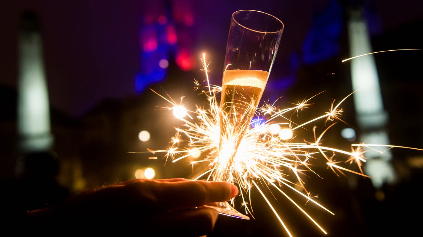 Mit einem Glas Champagner und einer Wunderkerze auf das neue Jahr anstoßen