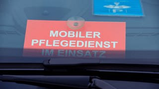 Ein Schild mit dem Schriftzug «Mobiler Pflegedienst im Einsatz» liegt in einem Auto