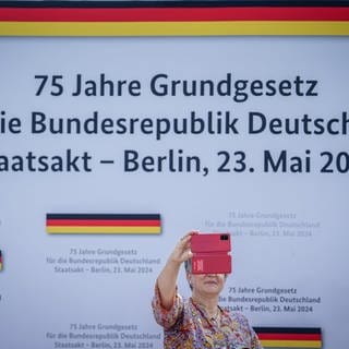 Eine Besucherin fotografiert sich beim Staatsakt zu «75 Jahre Grundgesetz» auf dem Forum zwischen Bundestag und Bundeskanzleramt.