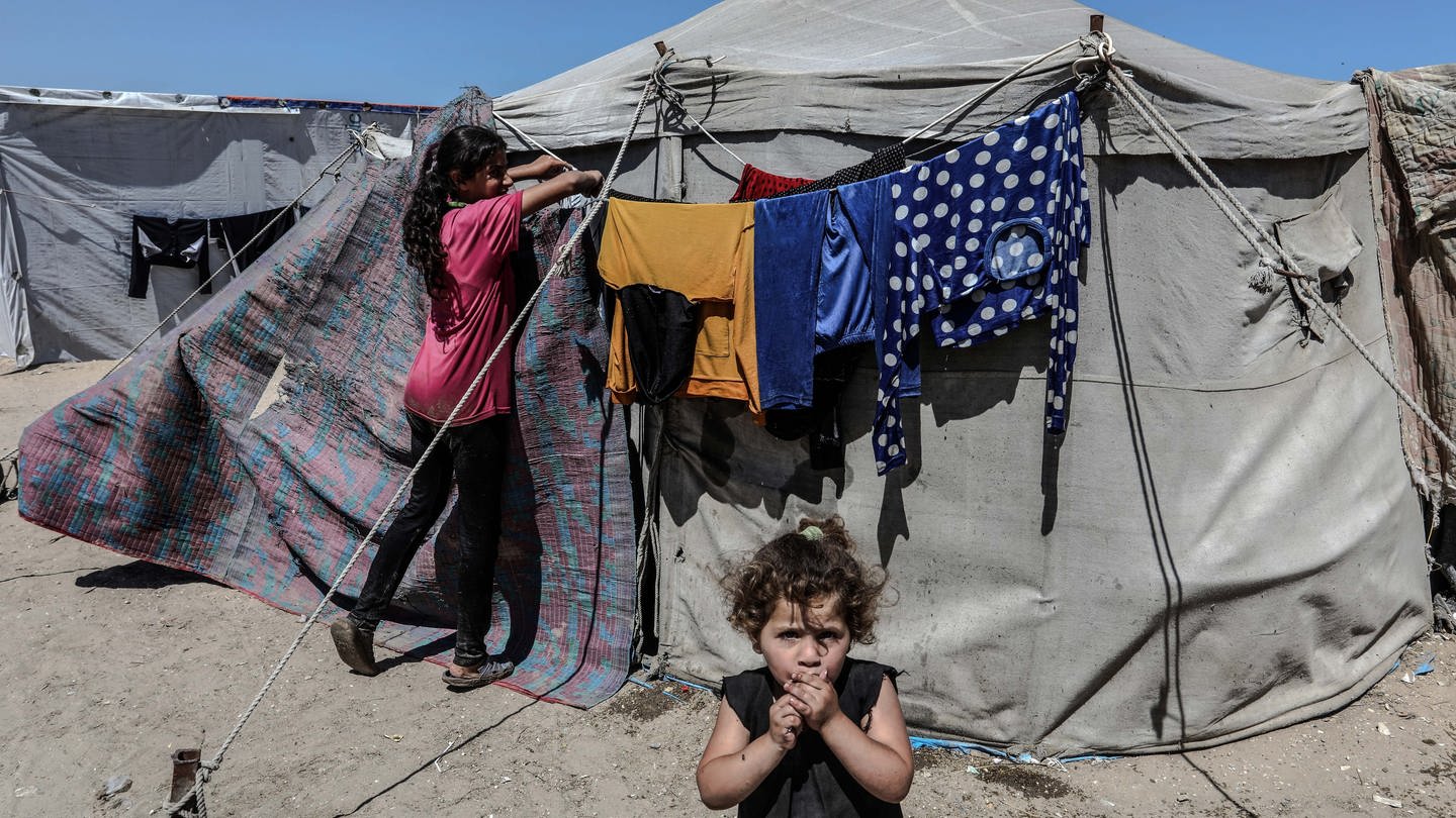 Geflüchtete Palästinenser hängen Wäsche vor einem Zelt an der Küste auf.
