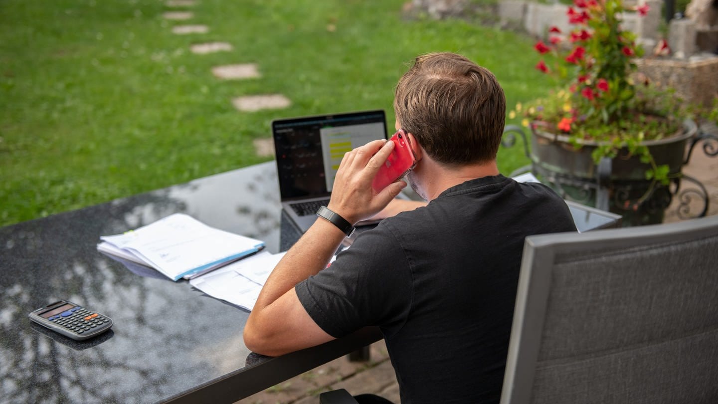 Ein Mann sitzt zuhause im Garten und arbeitet am Laptop. Fast jeder dritte deutsche Büroarbeiter ist auch im Sommerurlaub für den Job erreichbar