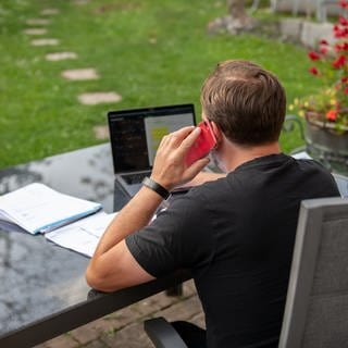 Ein Mann sitzt zuhause im Garten und arbeitet am Laptop. Fast jeder dritte deutsche Büroarbeiter ist auch im Sommerurlaub für den Job erreichbar