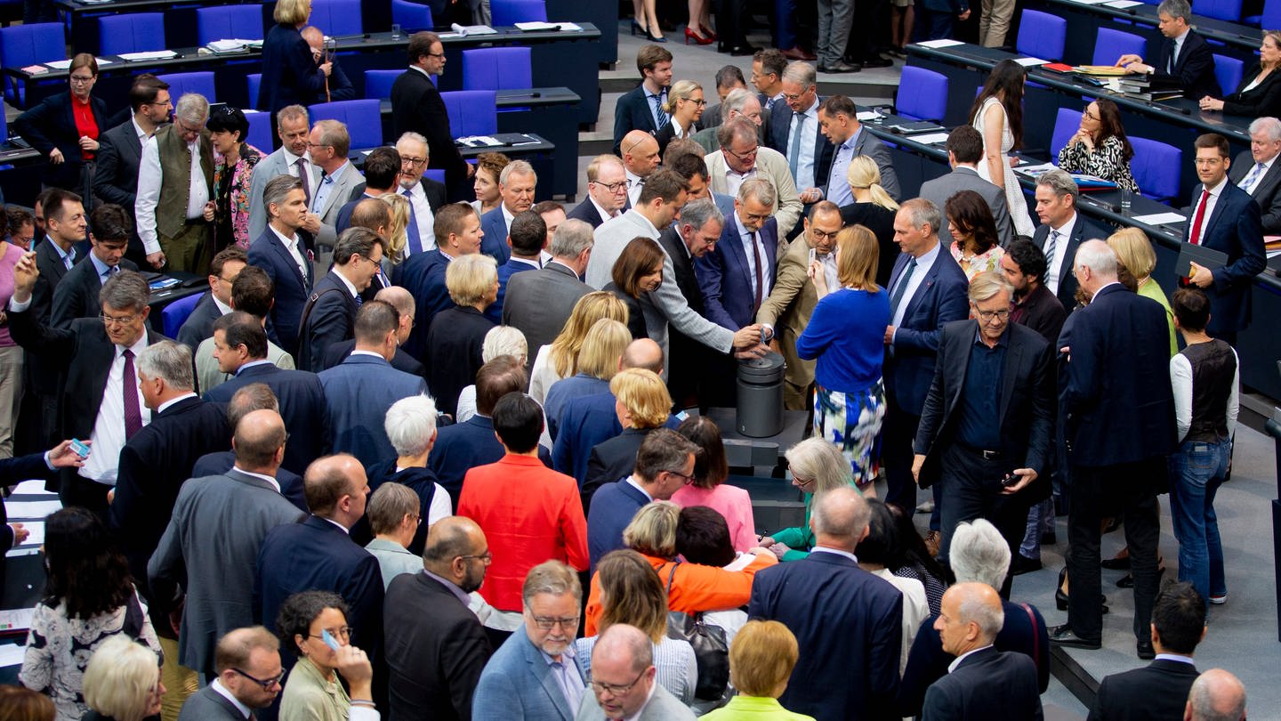 Mitglieder des Deutschen Bundestages stimmen im Plenum im Bundestag an einer Urne zum Asyl- und Aufenthaltsrecht ab.