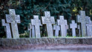 Grabkreuze am Kriegsgräber Denkmal auf einem Alten Friedhof.