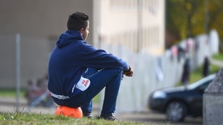 Ein jugendlicher Asylbewerber sitzt vor der Landeserstaufnahmestelle in Meßstetten (Baden-Württemberg) auf einem Ball.