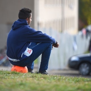 Ein jugendlicher Asylbewerber sitzt vor der Landeserstaufnahmestelle in Meßstetten (Baden-Württemberg) auf einem Ball.