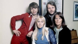 Die Bandmitglieder von ABBA schauen lächelnd in die Kamera.