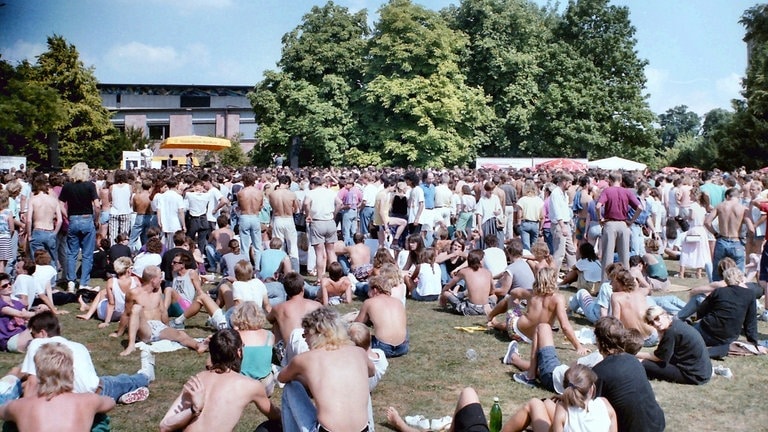 Viele Menschen sitzen 1989 im Park der Villa Berg in Stuttgart, hören gemeinsam Radio und feiern gemeinsam das Finale der SDR3 Hitparade TOP 1000 X