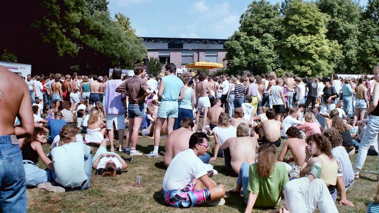 Viele Menschen sitzen 1989 im Park der Villa Berg in Stuttgart, hören gemeinsam Radio und warten auf das Finale der SDR3 Hitparade TOP 1000 X