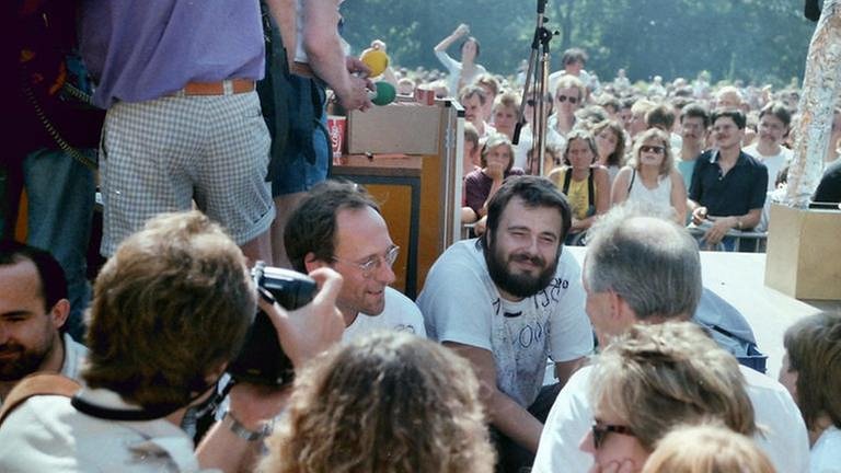 Nahaufnahme der SDR3 Moderatoren Stefan Siller (mitte-links) und Thomas Schmidt (mitte-rechts) umringt von Fans im Park der Villa Berg in Stuttgart bei der Finalparty der SDR3 Hitparade TOP 1000 X