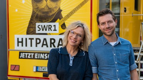 Die SWR1 Hitparaden Tour mit Stefanie Anhalt und Corvin Tondera-Klein vor einem gelben SWR-Fahrzeug macht Stopp in Aalen