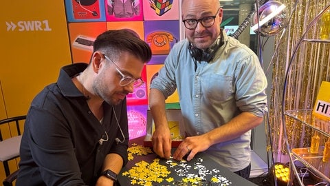 Max Oehl und Matthias Sziedat machen ein Puzzle im SWR1 Studio während der SWR1 Hitparade.