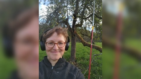 Lisa-Marie in Rudersberg mit Kopfhörern auf dem Kopf vor einem Apfelbaum in einem Obstgarten.