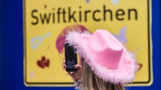 Ein Fan fotografiert in der Gelsenkirchener Innenstadt ein Schild mit der Aufschrift "Swiftkirchen". Die Konzerte von Taylor Swift in Deutschland haben Einfluss auf die SWR1 Hitparade.