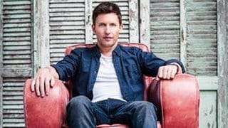 James Blunt sitzt in einem roten Sessel, 2013