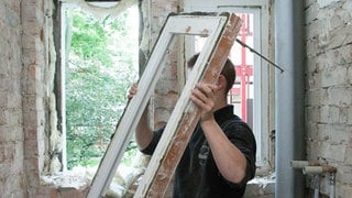 Ein Handwerker tauscht bei einer Sanierung ein altes Fenster aus - Wußten Sie: Ein Viertel der Wärme geht in einem normalen Einfamilienhaus über die Fenster verloren! So sanieren Sie richtig.