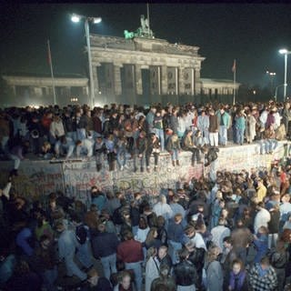 Menschen auf der Berliner Mauer vor dem Brandenburger Tor in der Nacht vom 9. auf den 10.11.1989.