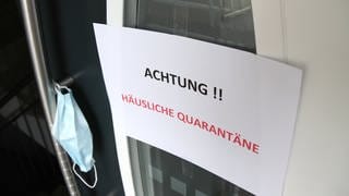 Ein Schild mit der Aufschrift "Häusliche Quarantäne" an der Eingangstür zu einem Wohnhaus