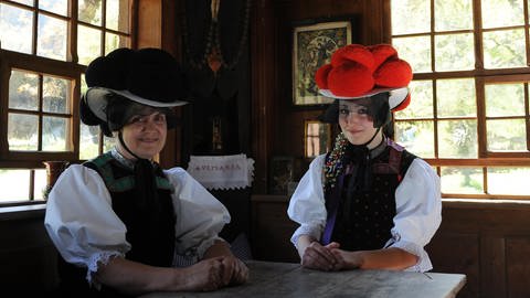 In Gutach in Baden-Wuerttemberg tragen zwei Frauen ihre Bollenhüte und ihre typische Schwarzwälder Tracht.