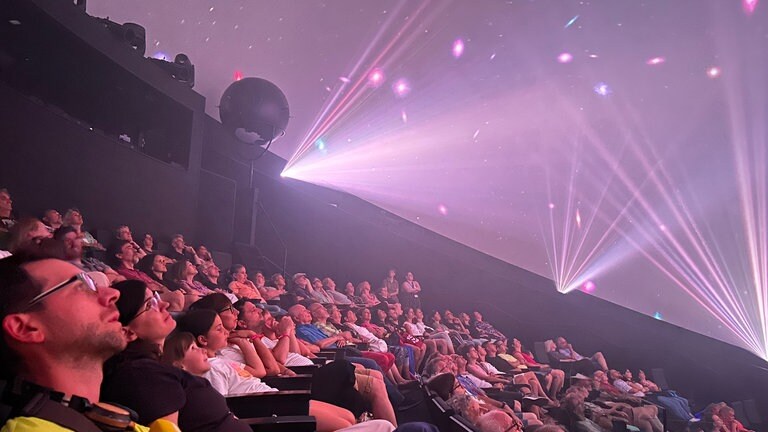 Der perfekte Tag mit SWR1 in der Experimenta Heilbronn. Unsere Gewinner sitzen im "Science Dome", einem großen 3D-Kino und schauen sich die eine Show mit der Musik des legendären Pink Floyd Albums "Dark Side of the Moon" an