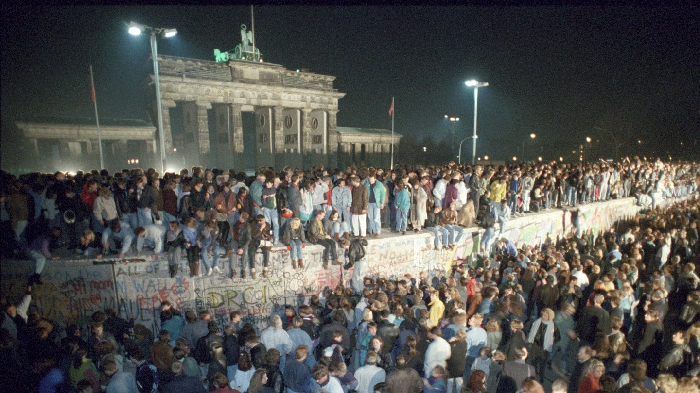 Menschen auf der Berliner Mauer vor dem Brandenburger Tor in der Nacht vom 9. auf den 10.11.1989.