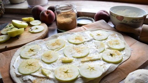 Süßer Flammkuchen mit Äpfeln belegt vor dem Backen