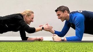 Der Athletiktrainer des SC Freiburg, Daniel Wolf, gibt SWR1 Moderation Laura Zacharis Trainingstipps für mehr Bewegung und Sport im Alltag. Gegenüber auf dem Boden klatschen sie sich ab. Wie gelingt es fit zu werden?