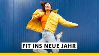 Eine junge Frau mit gelber Winterjacke und Jeans springt vor einem blauen Hintergrund in die Luft. Startet fit ins neue Jahr mit SWR1! Mit gesunden Rezepten, und den besten Fitness-Tipps.