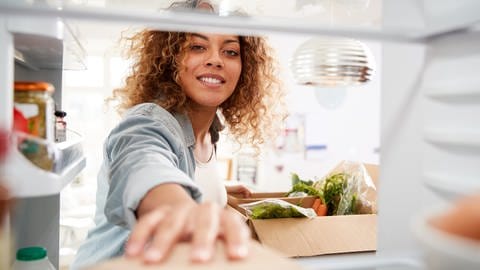 Eine Frau legt Lebensmittel in den Kühlschrank